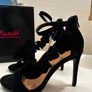New black high heel. Zips behind ankle. Black fabric strap goes across foot.